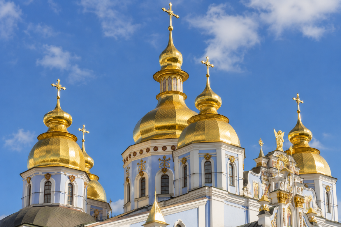 Золоті куполи православного собору на тлі блакитного неба в Україні.